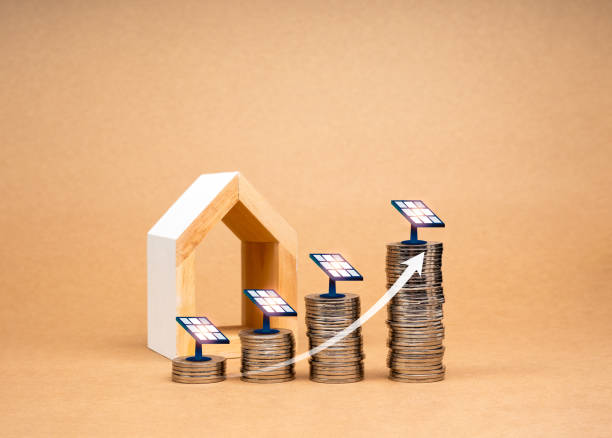des dépenses durables, des économies sur les coûts d’électricité, des concepts qui sauvent le monde. flèche vers le haut sur la pile de pièces de monnaie comme graphique de croissance avec des panneaux solaires près d’une maison en bois blanc m - devis panneaux solaire photos et images de collection